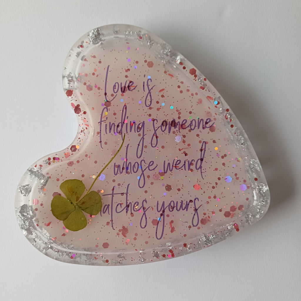 Original handmade resin artwork with a pressed four-leaf clover inside a heart, the design inspiration for The Neat Rack's Love Is collection