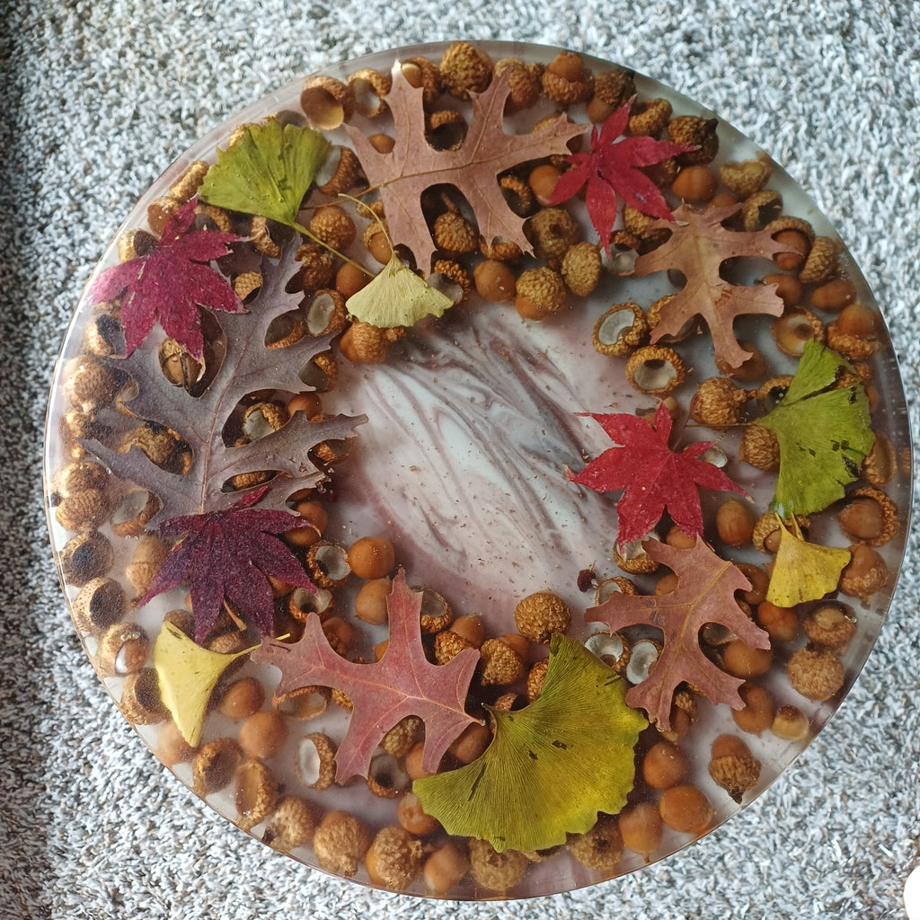 Resin side table with real autumn leaves and acorns sealed in epoxy, close-up of the leaf wreath